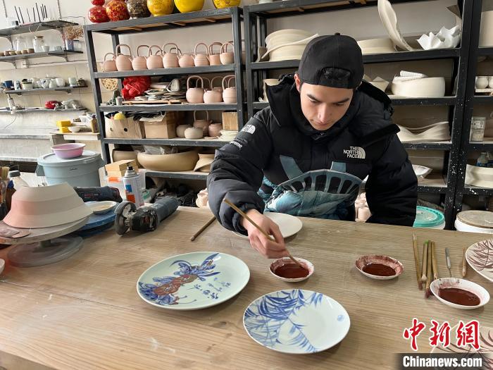 图为法国“00后”夏天意在案台前用青花颜料在素坯上勾勒“竹”的图案。 李韵涵 摄