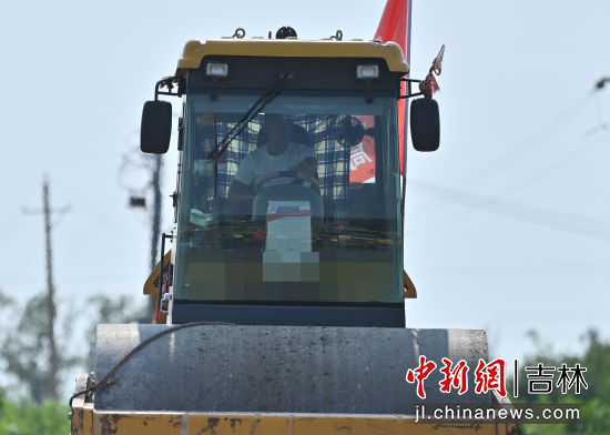 全线首段路面基层施工现场，轧道机司机在后车窗自制一个“窗帘”来遮挡阳光。